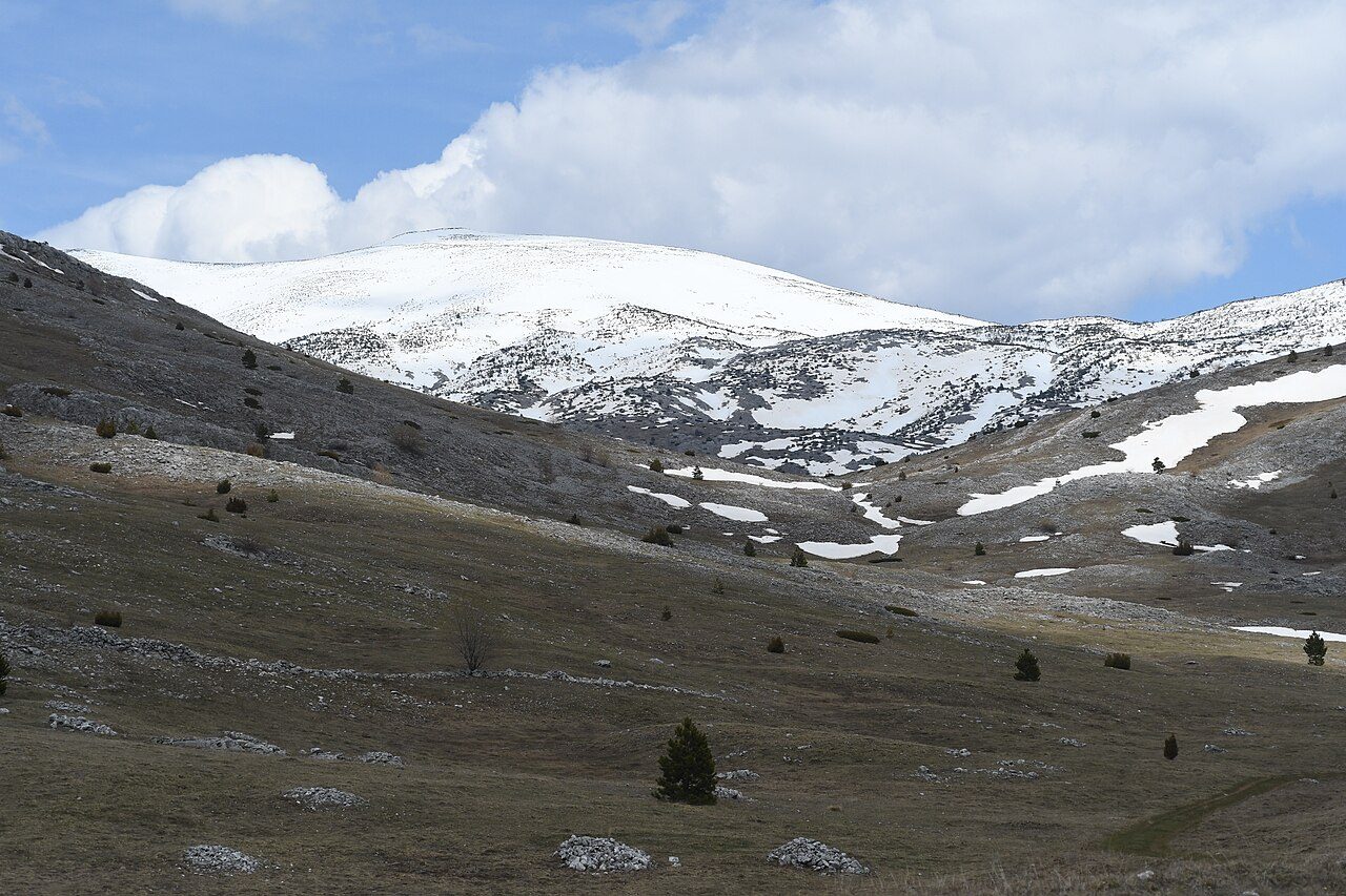 Open highland pasture below the snowy ridge of Bjelašnica