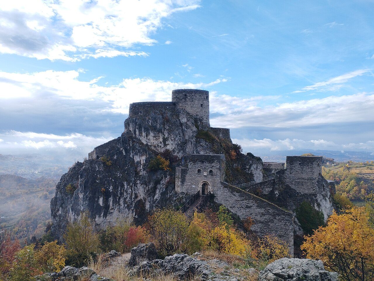 Srebrenik Fortress on top of a rocky crag, with autumn trees below