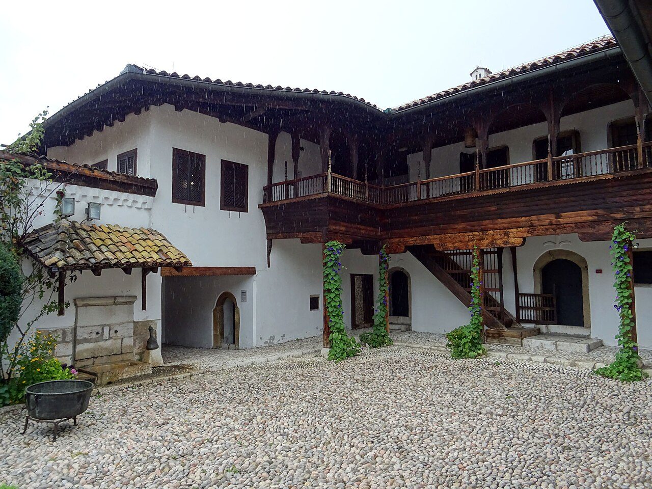 The pebbled courtyard of Svrzo's House, with white walls and dark wooden balconies