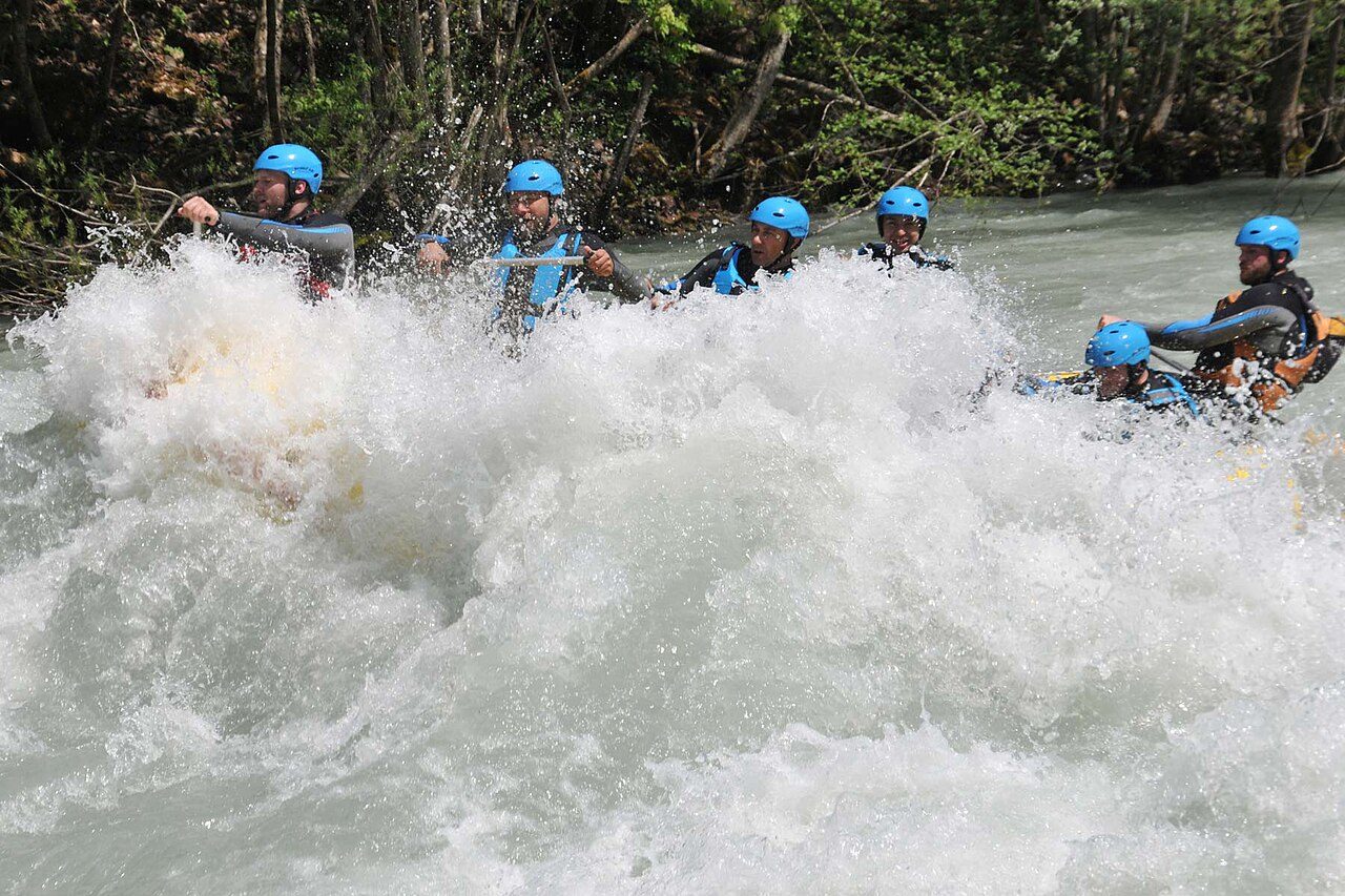 A rafting crew in blue helmets paddling through white water on the Tara