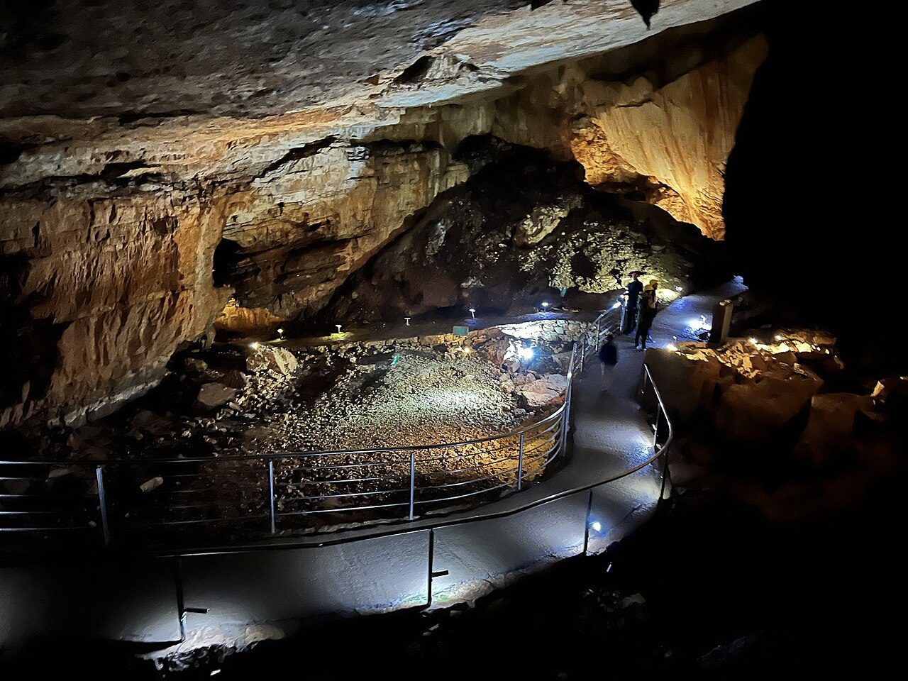 A lit walkway winding through a large chamber inside Vjetrenica Cave