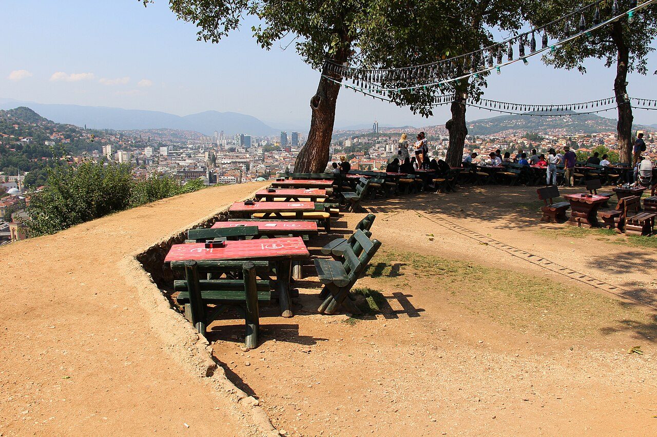 Picnic tables under the trees at the Yellow Fortress, looking out over Sarajevo